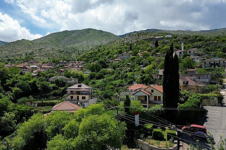 Houses of Lazarat spread across a green hillside beneath the mountains